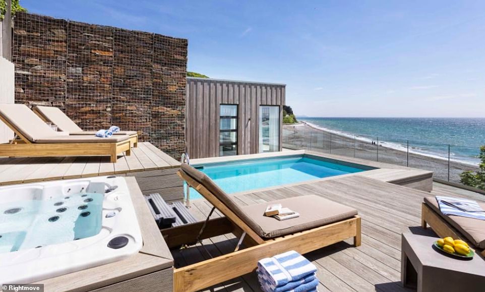 It features a vast seafront terrace decked out with a heated outdoor pool, a hot tub, pool house and fire pit. Steps lead directly down to the beach and shoreline